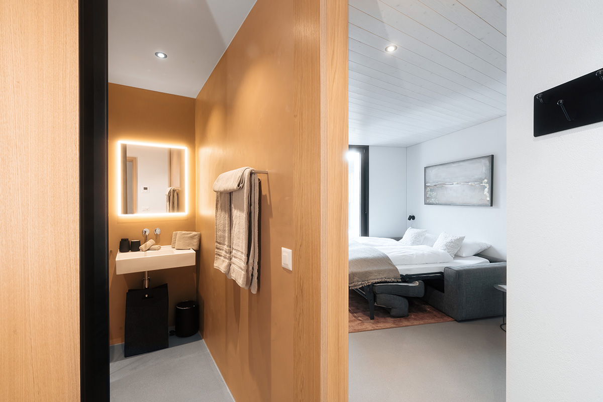 Stylish vacation apartment in Andermatt in Switzerland with minimalist bathroom furnishings and a bedroom in white and black.