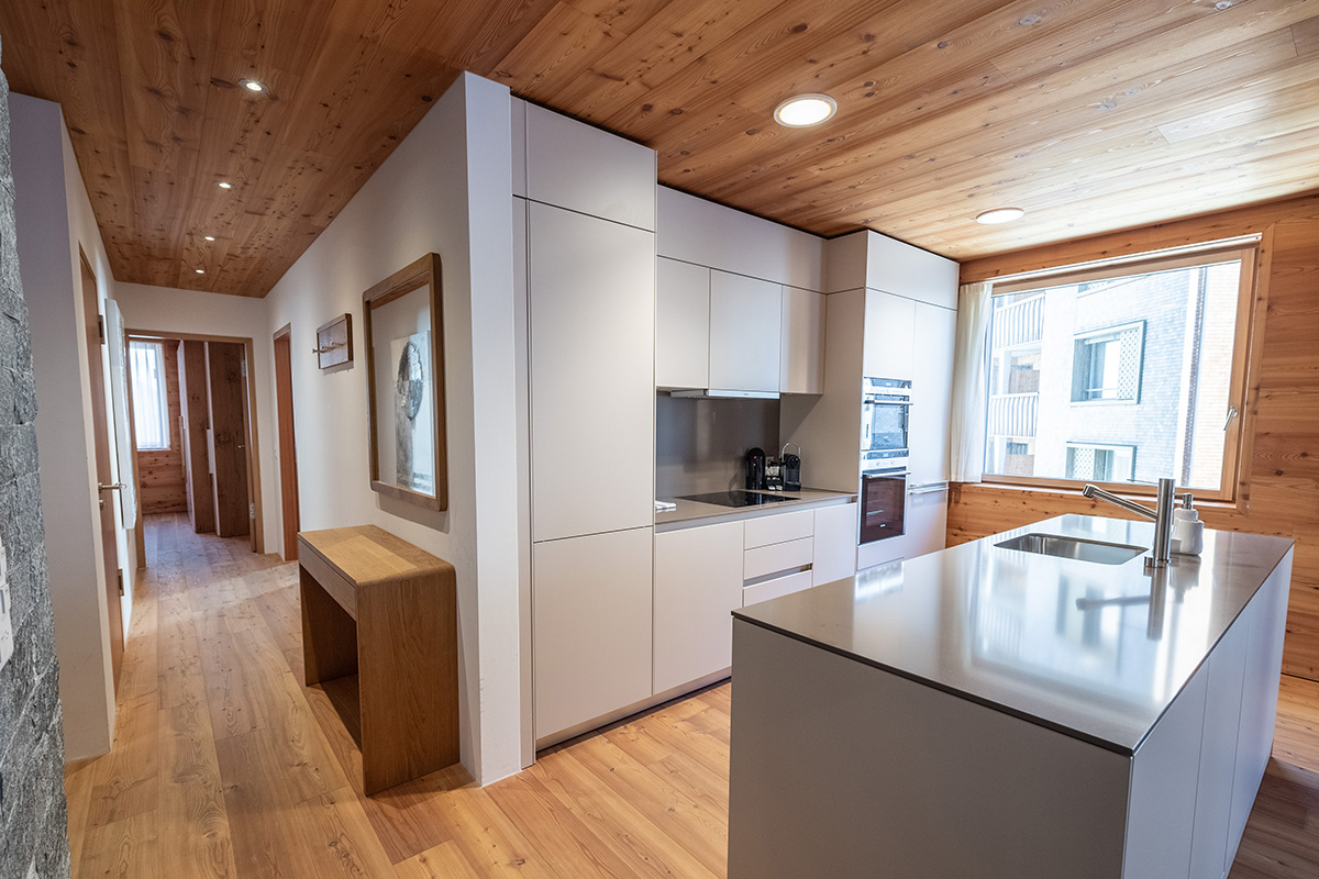 A vacation apartment in Switzerland with a well-equipped kitchen, an island block and large windows for natural light.