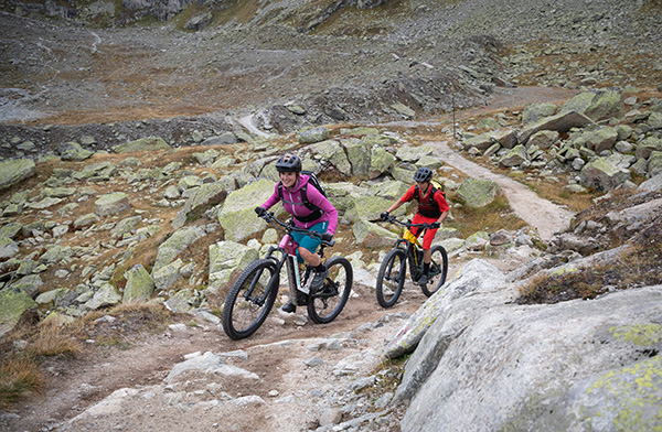 A mountain biker on a steep trail in the mountains, an adventure on a summer vacation in Switzerland.