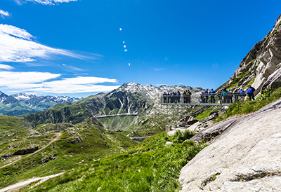 Tourists are enjoying a view of the snowy mountains in Andermatt from a vantage point.