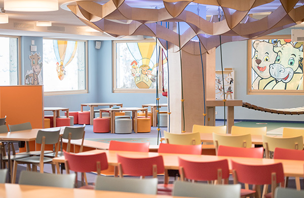 Colorful childcare facility with play tables and child-friendly furniture, ideal for a family vacation in Switzerland.