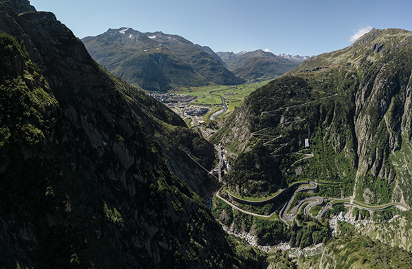 An aerial view of a winding mountain road in the middle of the mountains - the perfect area for summer vacation in Switzerland.