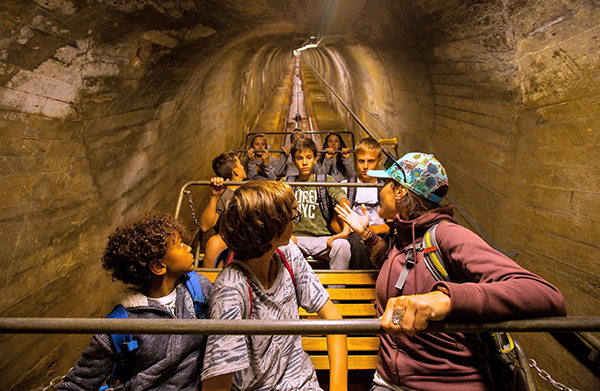 Children and adults on an underground ride enjoy exciting experiences on a family vacation in Switzerland.