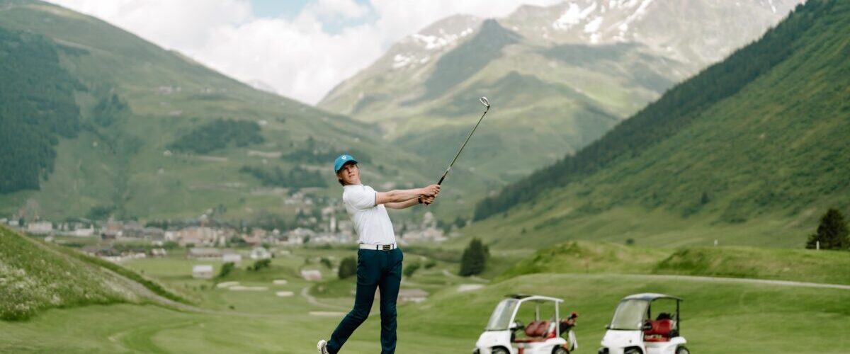 Golfer in the swiss alps mountains with andermatt town in the background