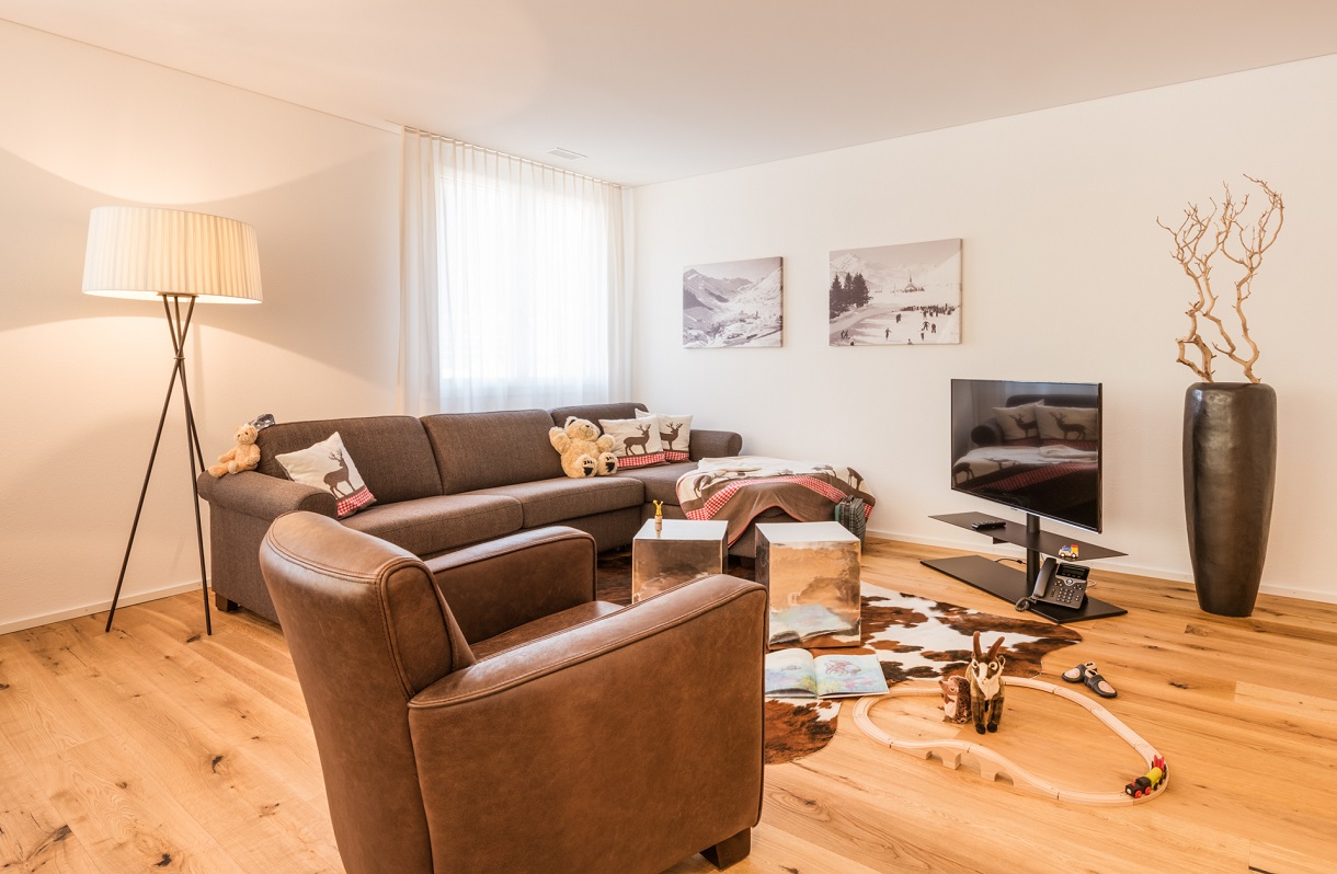 living room with brown chairs and sofa, wooden floor