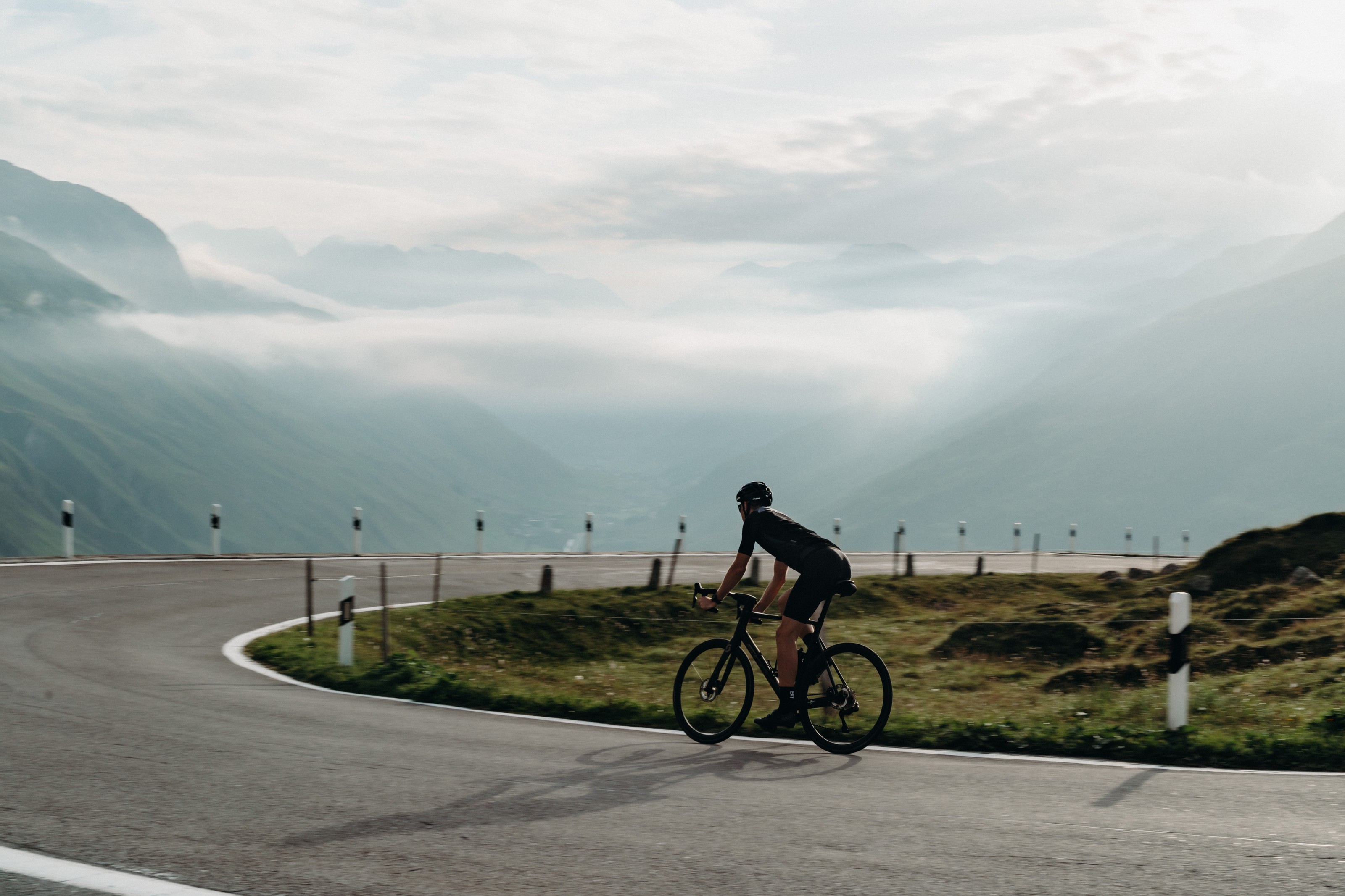 Road cyclist ascending a mountain pass near Andermatt above the clouds